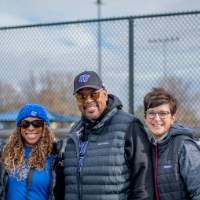 Five alumni smile for a group photo at the tailgate